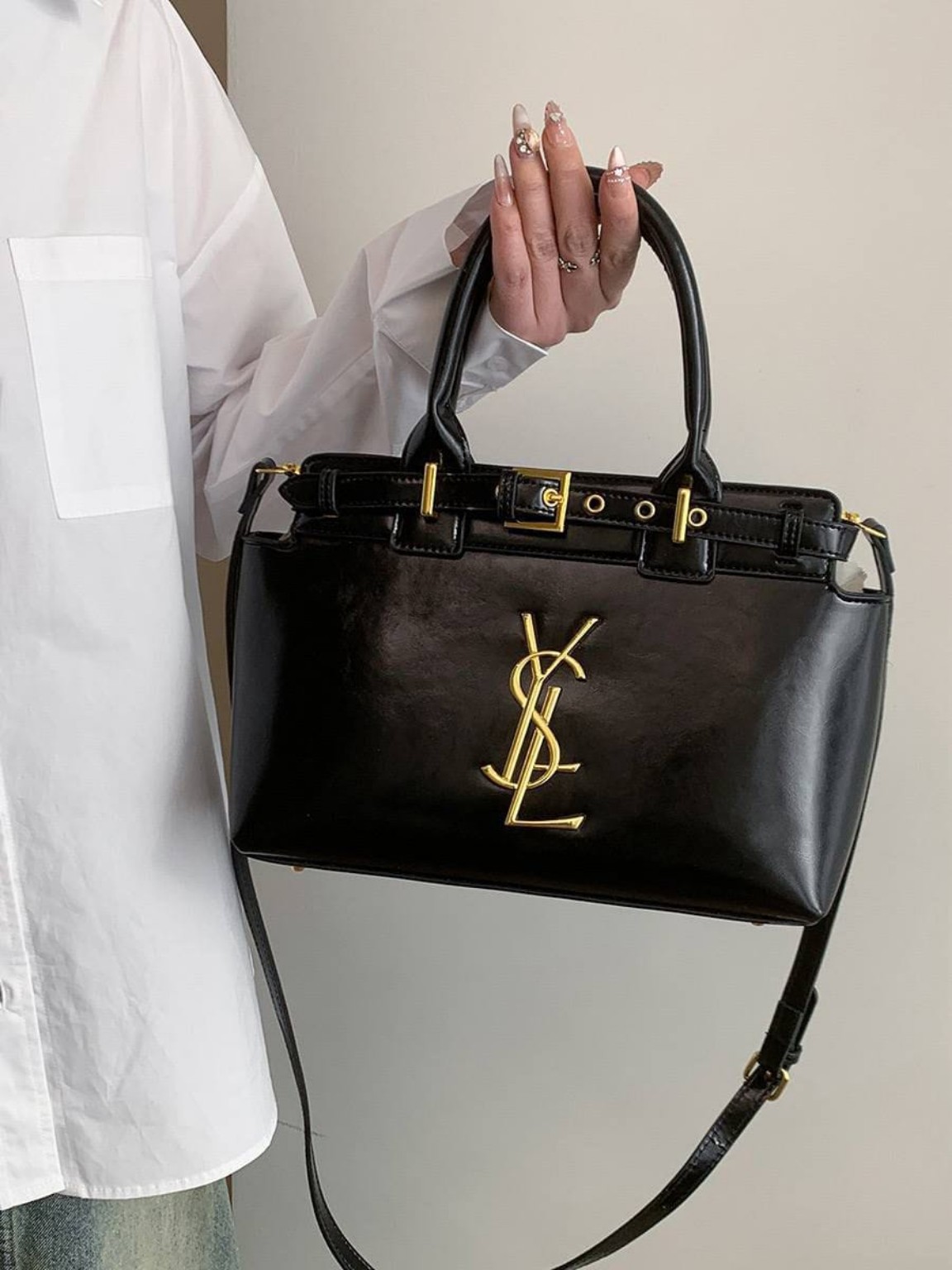 Black structured handbag with gold-tone hardware, top handles and a shoulder strap