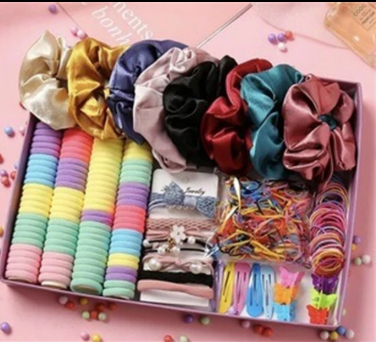 Pink gift box filled with pastel kids scrunchies, elastic hair bands, clips and decorative hair ties